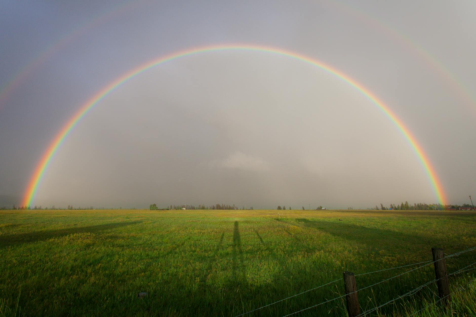Tęcza nad spokojnym gospodarstwem rolnym na otwartym polu