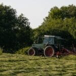 Zgrabiarka karuzelowa: jak ustawić palce i prędkość, by nie zanieczyszczać paszy Ciągnik z maszyną rolniczą pracuje na zielonej łące latem