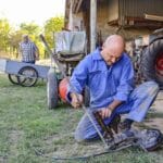 Dwóch mechaników naprawia maszynę rolniczą na podwórzu