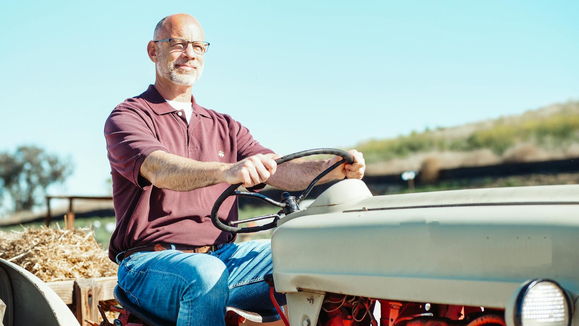 Starszy rolnik na zabytkowym traktorze pracuje w polu w słoneczny dzień
