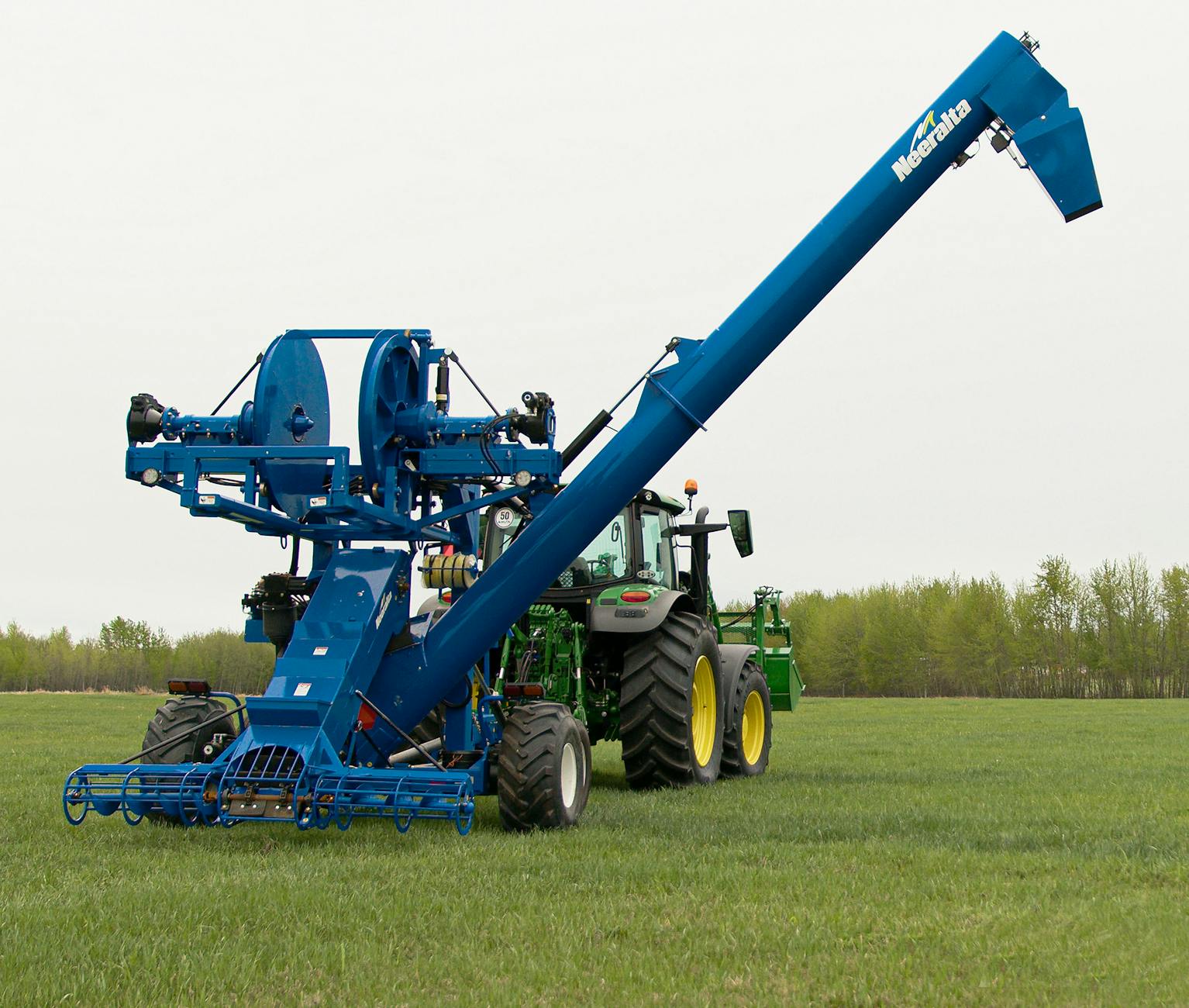 Traktor z niebieską maszyną uprawową pracuje na otwartym polu