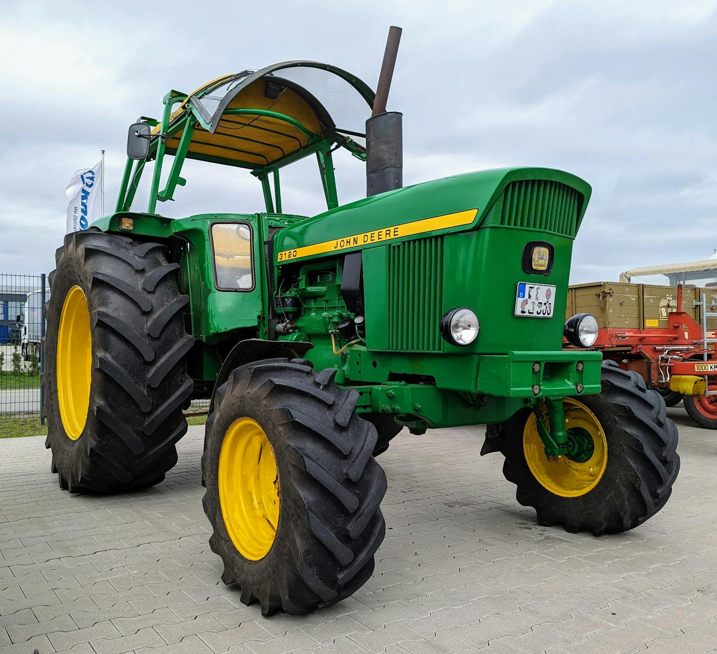 Zielony ciągnik John Deere z dużymi oponami na placu w niemieckiej wsi