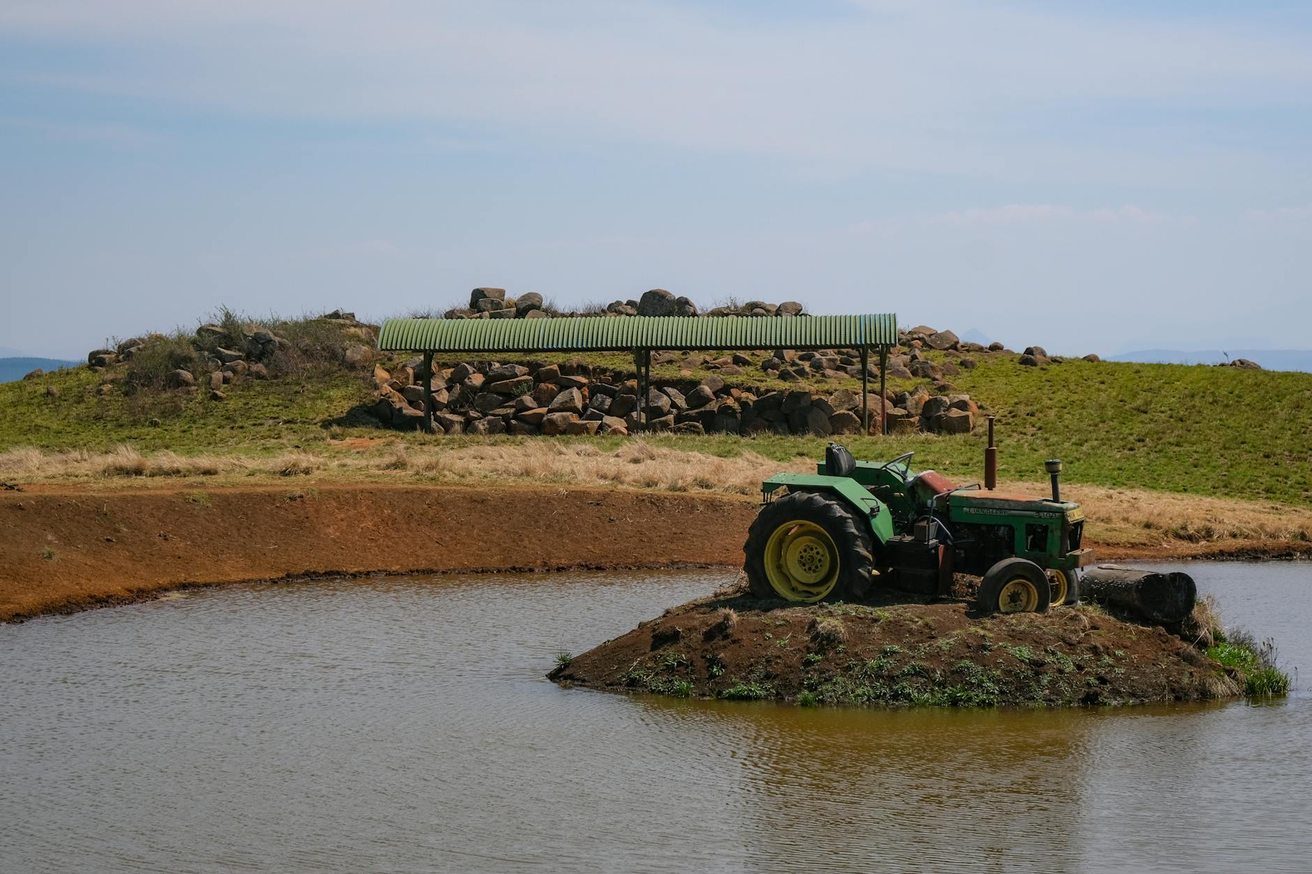 Zielony ciągnik Ursus na małej wyspie pośrodku stawu na wsi