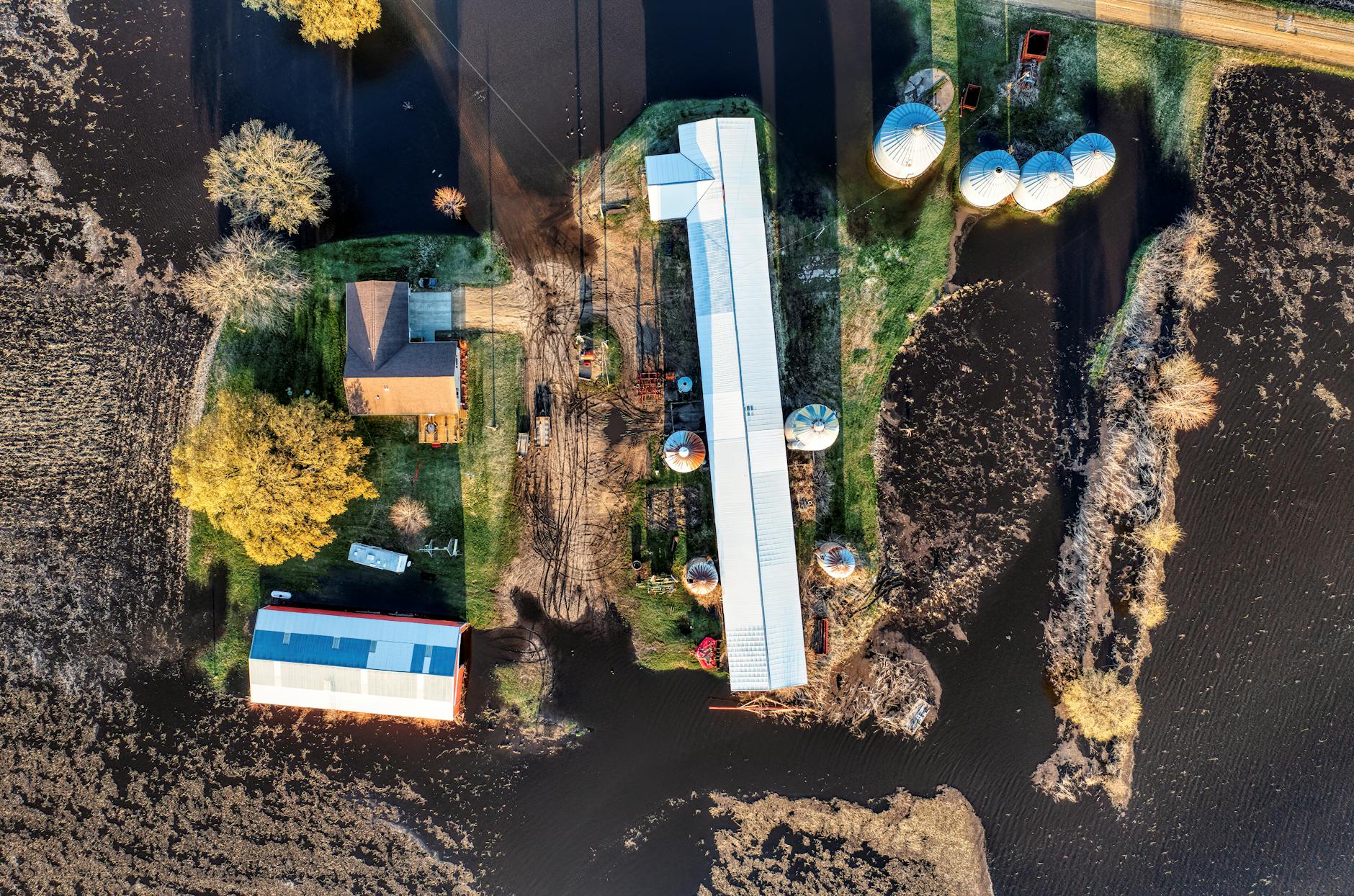 Zalane pola uprawne wokół wiejskiego gospodarstwa z silosami