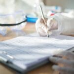 Pracownik laboratorium w rękawiczkach wypełnia dokumentację HACCP